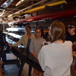 Coxswain Chloe Thacker (center right, with back turned) briefs members of the Varsity 8 about the high wind conditions along the 5-km course. Left to right: Sylvia Sarnik, Claire Martin-Doyle (head coach), Priya Veeraraghavan (captain), Sharon Wu (captain), Kelly Barton, Valerie Hunter, Elizabeth Martin, and Annika Rollok. “Wear layers,” says Thacker. “Be ready for water in the boat.” (Photo: Sam Hunter Magee/Arts at MIT)