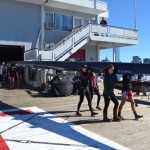 Members of the Varsity 8 lineup prepare for race time. Valerie Hunter (front left) and Kelly Barton carry bow 39, a 200-pound boat, with help from Michelle Lauer (back left) and Sylvia Sarnik. Navigating the shell across the busy dock isn’t easy but directives like, “Ready up in the bow, swing to Boston,” get the job done. (Photo: Sam Hunter Magee/Arts at MIT)