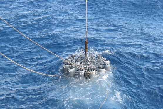 Scientists on an oceanographic research ship lower a rosette of 24 bottles into the ocean to capture samples of wild microbes in their natural habitat. (Photo: Paul Berube/MIT)